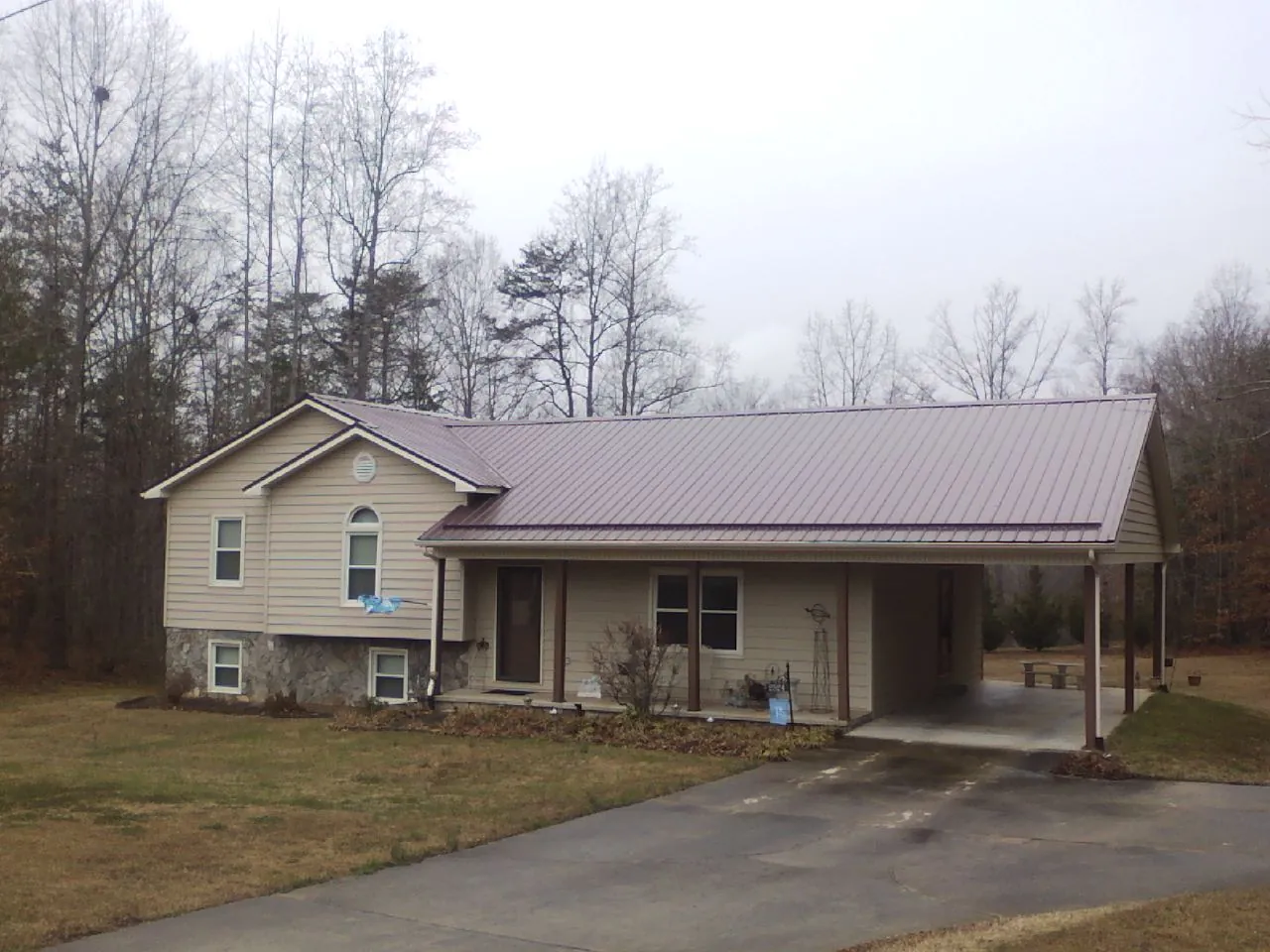Burgundy metal roof on a tan split level home with an attached carport in Damascus