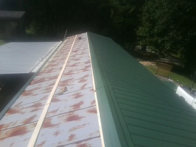 Old rusted panels beside newly installed green metal roofing — Wind Damage Roof Repair by Roofing Brothers in Damascus