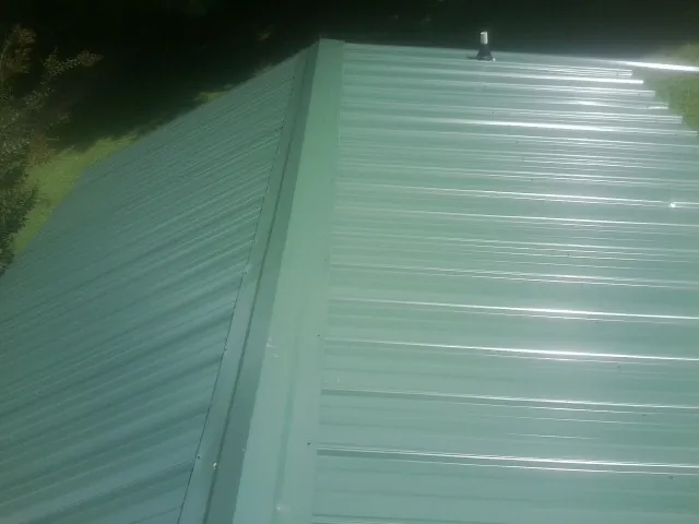 New green metal panels meeting at the ridge of a roof — Flat Roof Repair work by our crew in Damascus