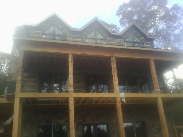 Dormers and porch framing on a large log home under construction — Roof Coating work by our crew in Damascus